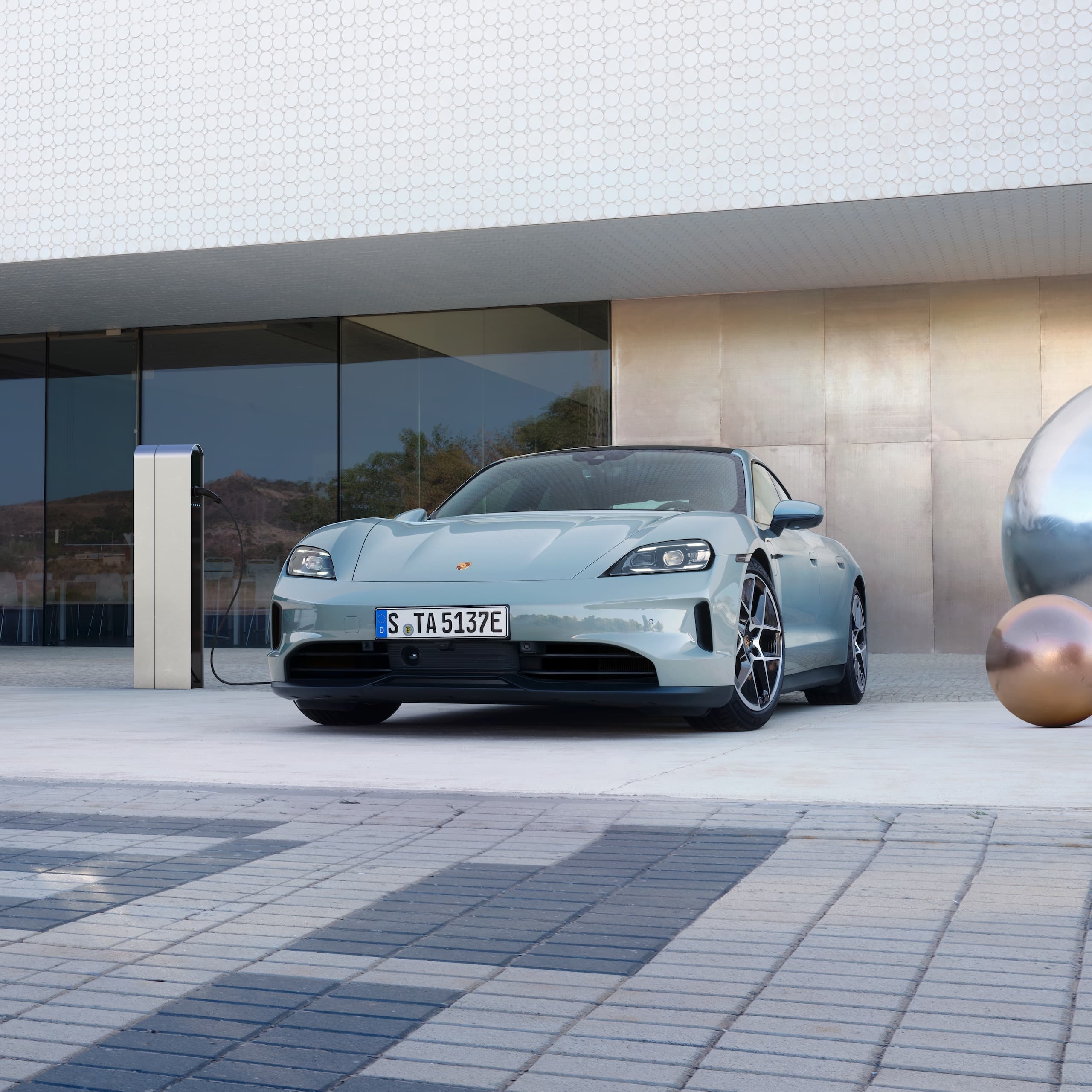 Ein Porsche Taycan parkte draußen vor einem modernen Gebäude.